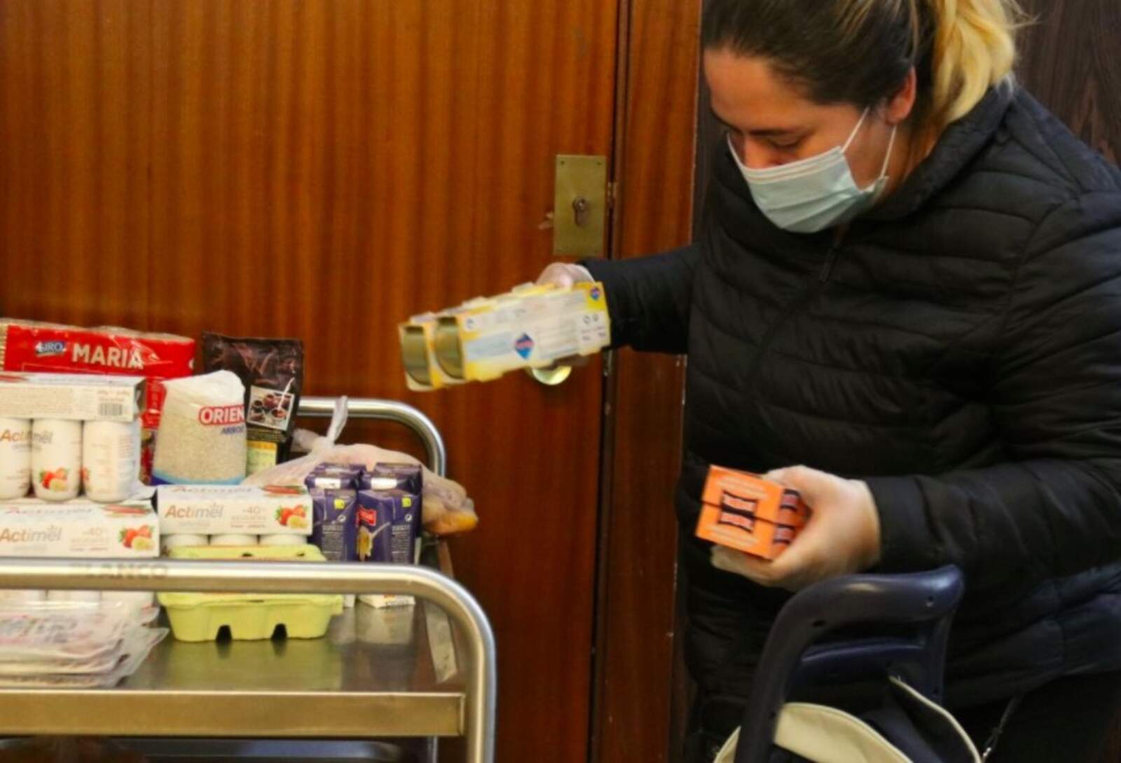 Una dona omple un carro de menjar a un punt de distribució d'aliments de Càritas