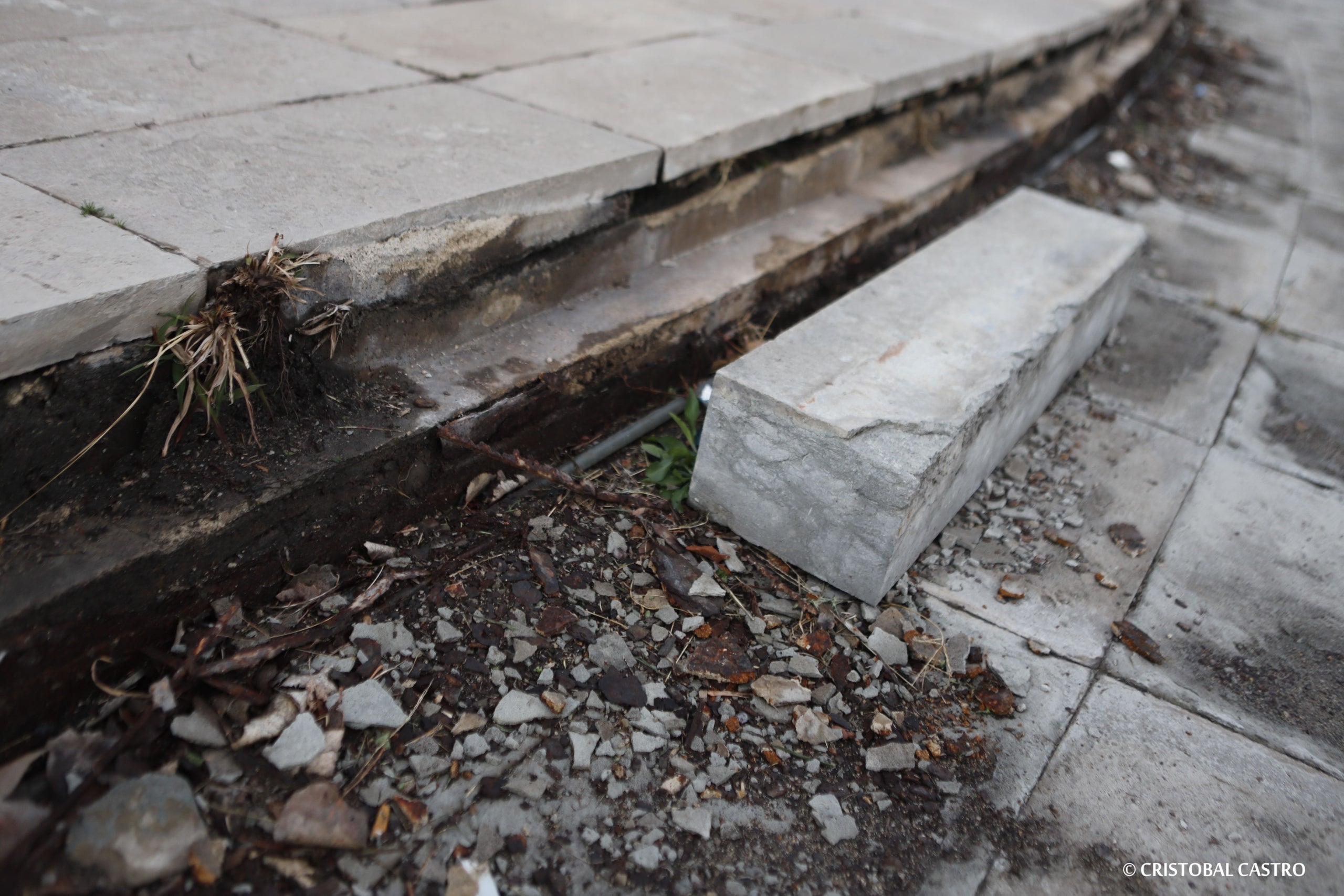 Estat en què es troba la plaça de la Dona Treballadora de Terrassa. L'incivisme i la falta de manteniment han deixat en un estat deplorable la rotonda i el monument. Les rajoles han anat desapareixent, els blocs de ciment han caigut, i els cables s'han despenjat. Ja no només és una qüestió estètica, sinó que representa un perill per a la seguretat dels vianants, i requereix una intervenció urgent, almenys de neteja i sanejament | Cristóbal Castro