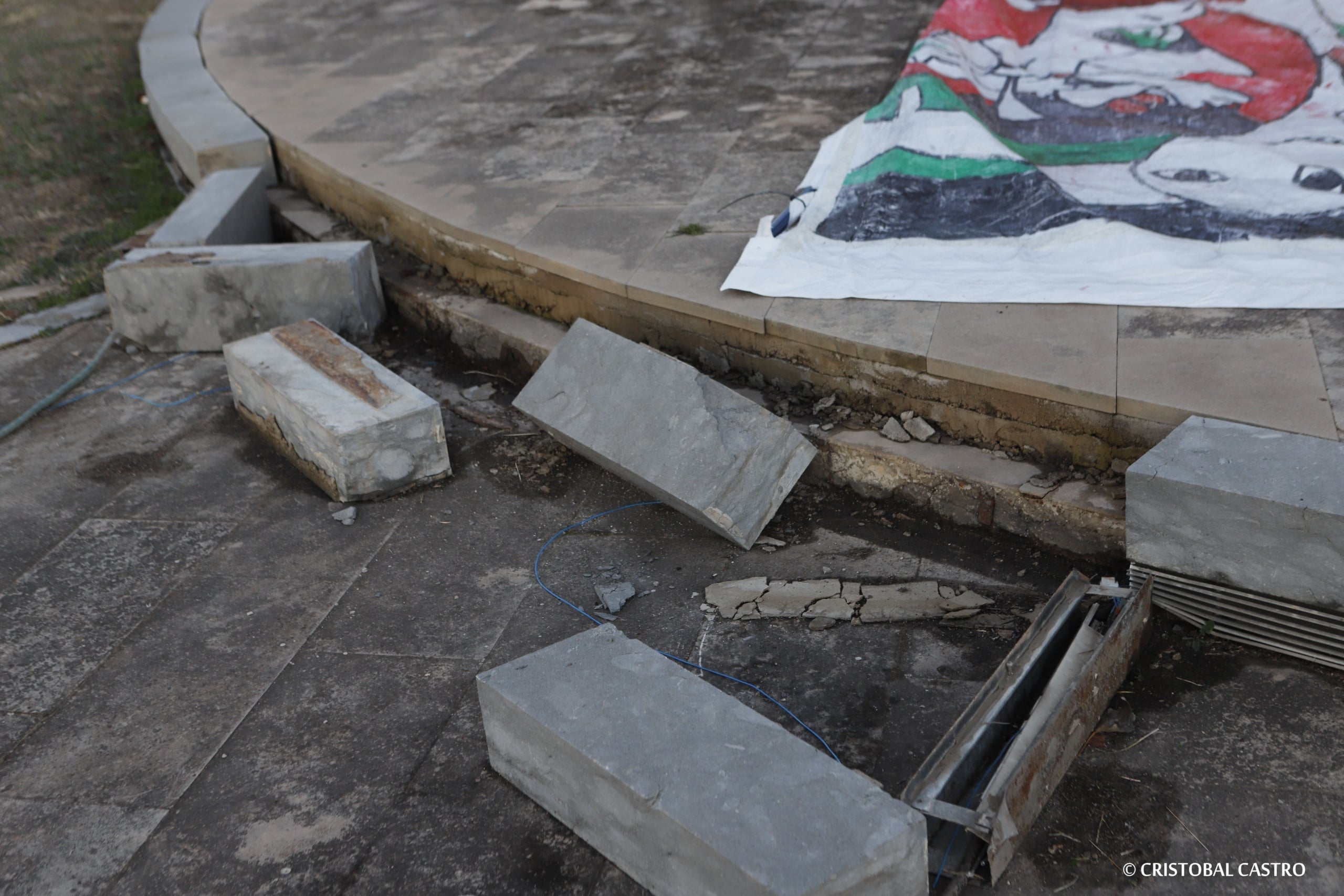 Estat en què es troba la plaça de la Dona Treballadora de Terrassa. L'incivisme i la falta de manteniment han deixat en un estat deplorable la rotonda i el monument. Les rajoles han anat desapareixent, els blocs de ciment han caigut, i els cables s'han despenjat. Ja no només és una qüestió estètica, sinó que representa un perill per a la seguretat dels vianants, i requereix una intervenció urgent, almenys de neteja i sanejament | Cristóbal Castro