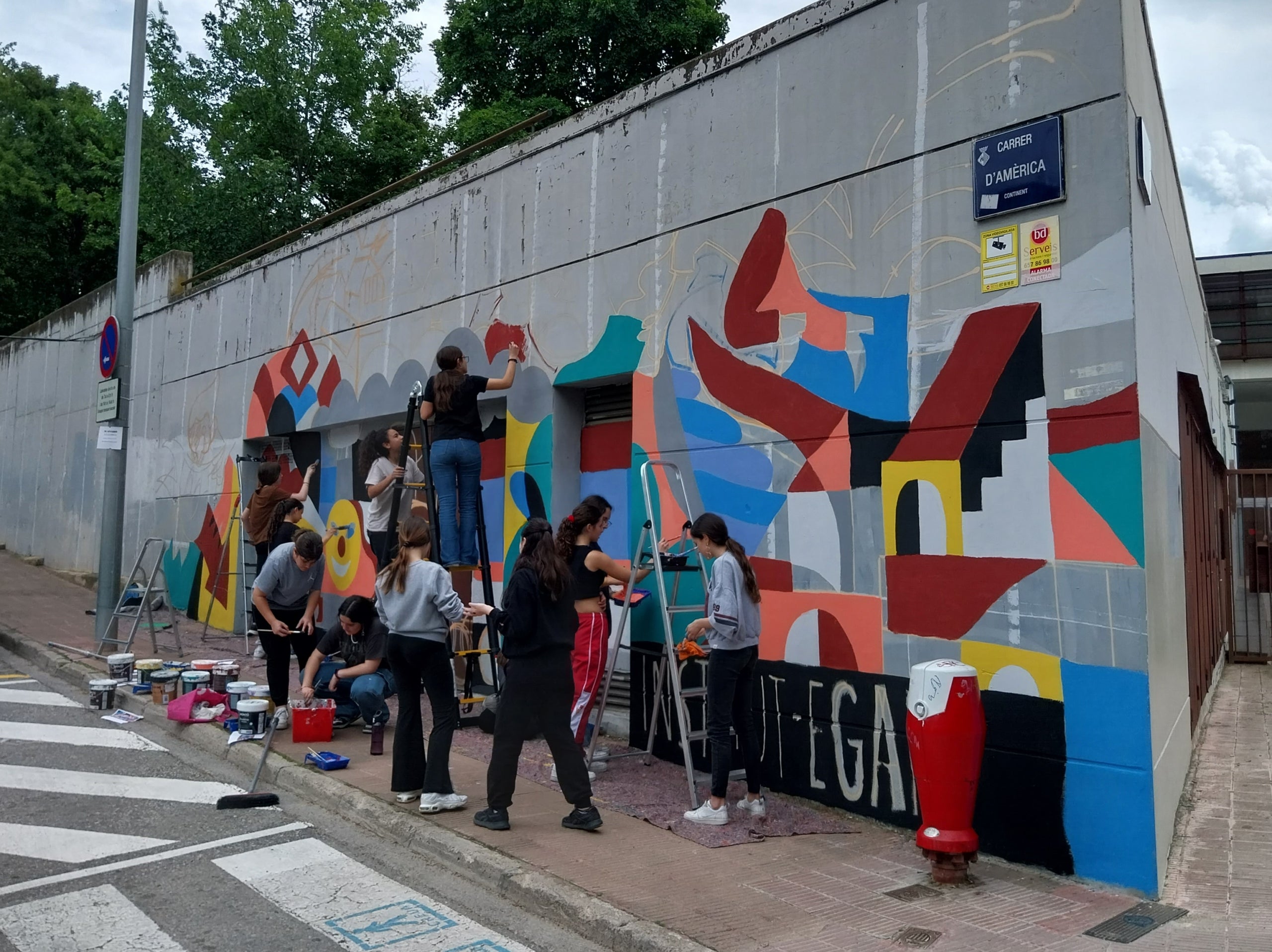 Estudiants de l'Institut Ègara pintant el mural a la paret del centre, amb l'ajuda de Pep Walls | Cedida