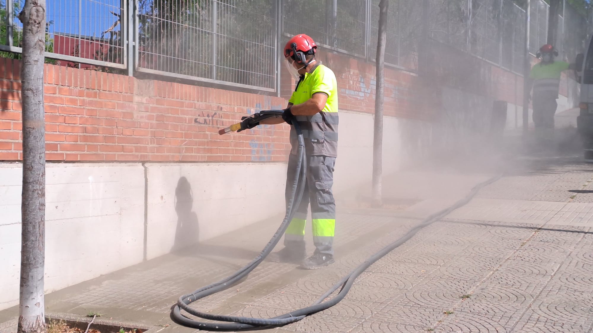Operari netejant els grafits d'una paret d'escola al carrer de Badalona de Terrassa | Oriol Manrique