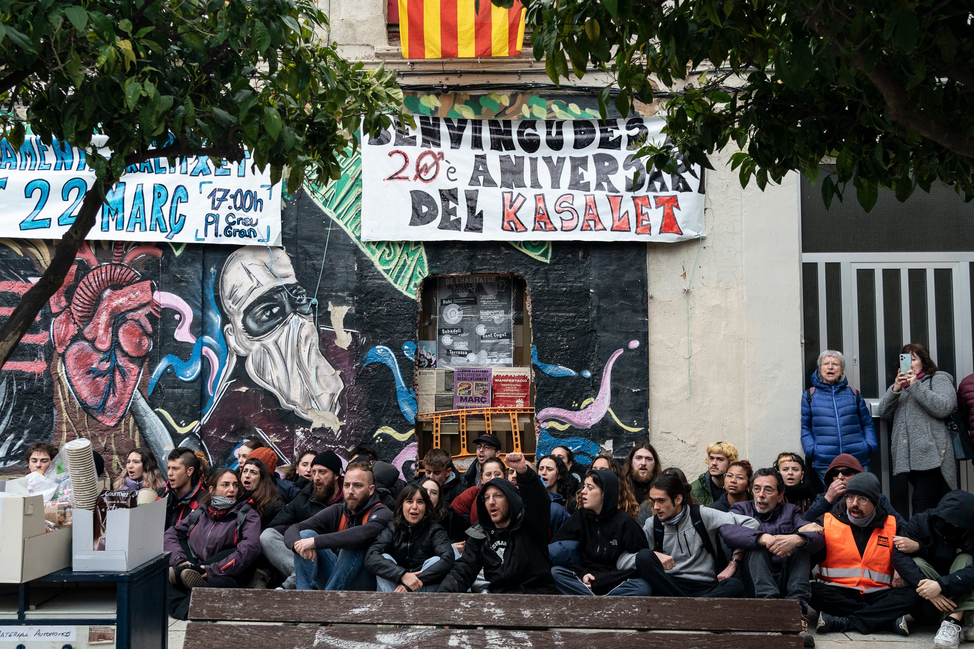 Aquest dimarts, dia 25 de març, s’ha produït el desallotjament del Kasalet i del Kalitxet a Terrassa. Hi ha hagut un amplíssim dispositiu dels Mossos d’Esquadra, que ha bloquejat el pas de vianants i vehicles durant més de dues hores la zona de la placeta de la Creu Gran, en ple Centre de la ciutat. Els membres dels centres okupats han ofert una resistència passiva, col·locant-se davant de les portes d’accés i obligant als agents a arrencar-los un a un. Finalment, han pogut rebentar les dues portes i entrar als edificis, i s’han identificat sis persones.