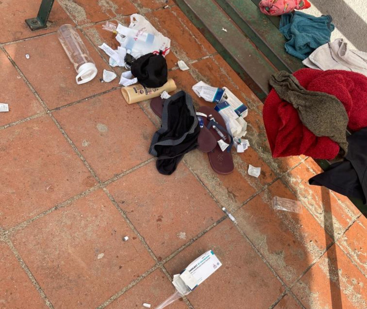 Cajas de medicamentos ropa y suciedad en un banco de la plaza Bòbila Segués | Cedida