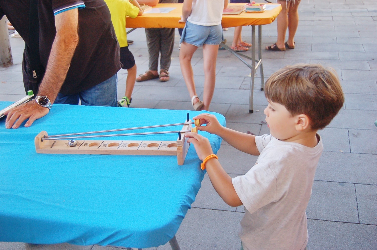Aquesta setmana, fins al dia 5 de setembre, la plaça Vapor Ventalló acull la 9a edició de la Setmana de Jocs al Carrer, organitzada per l’Associació Terrassenca de Jocs – Vadejoc. Aquesta iniciativa vol acostar el joc a l’espai públic, vol fomentar la participació familiar i la cohesió social a través d’activitats gratuïtes i inclusives. Al llarg de cinc dies, la plaça s’omple de jocs tradicionals, jocs de taula, jocs d’habilitat i tallers de joguines. A més, com a novetat, enguany tenim un campionat del joc de la botifarra o la presentació de nous jocs creats a Terrassa. Cada jornada es tanca amb una sessió de contacontes a càrrec de l’Associació Vet Aquí Que.