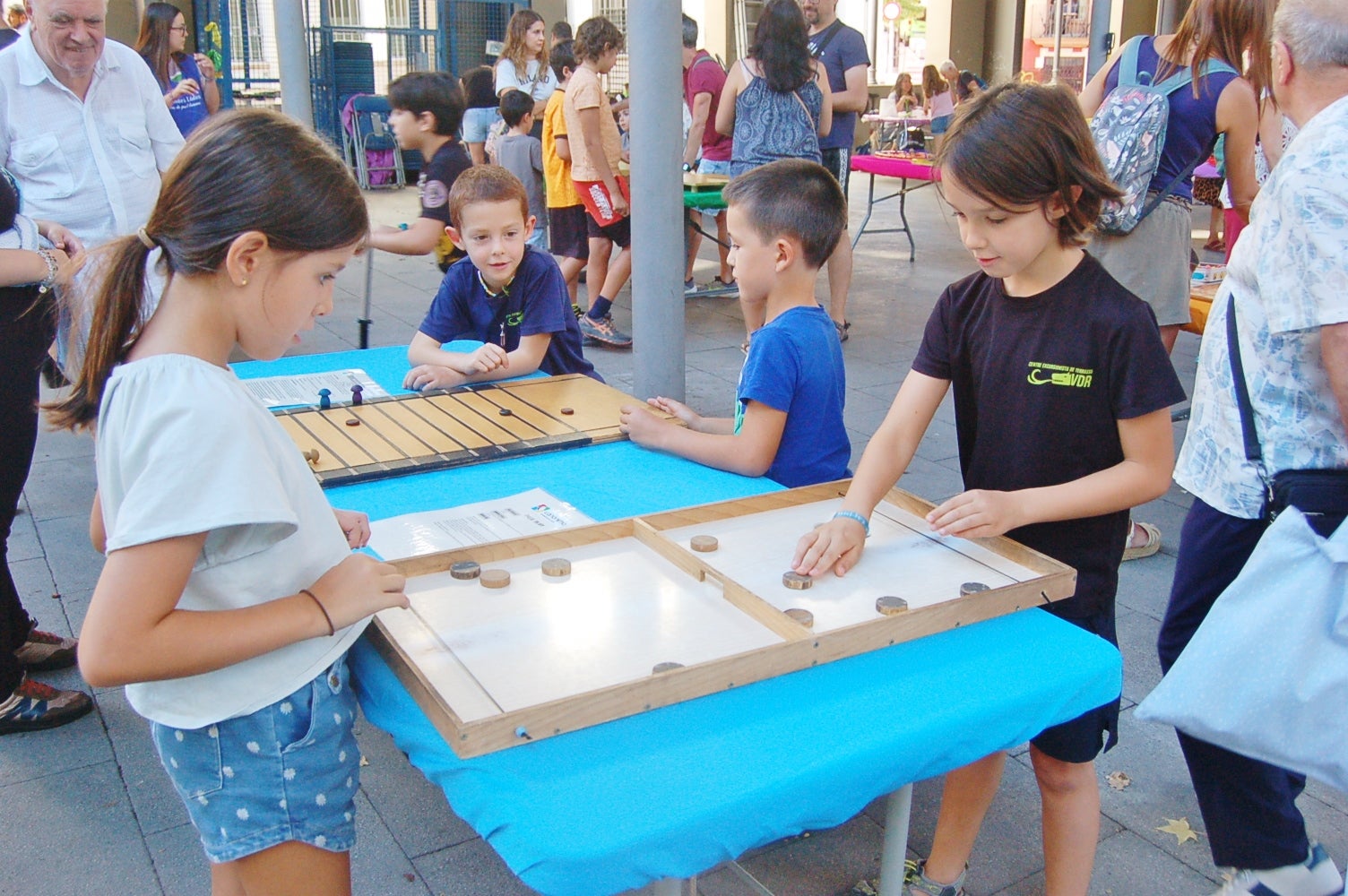 Aquesta setmana, fins al dia 5 de setembre, la plaça Vapor Ventalló acull la 9a edició de la Setmana de Jocs al Carrer, organitzada per l’Associació Terrassenca de Jocs – Vadejoc. Aquesta iniciativa vol acostar el joc a l’espai públic, vol fomentar la participació familiar i la cohesió social a través d’activitats gratuïtes i inclusives. Al llarg de cinc dies, la plaça s’omple de jocs tradicionals, jocs de taula, jocs d’habilitat i tallers de joguines. A més, com a novetat, enguany tenim un campionat del joc de la botifarra o la presentació de nous jocs creats a Terrassa. Cada jornada es tanca amb una sessió de contacontes a càrrec de l’Associació Vet Aquí Que.