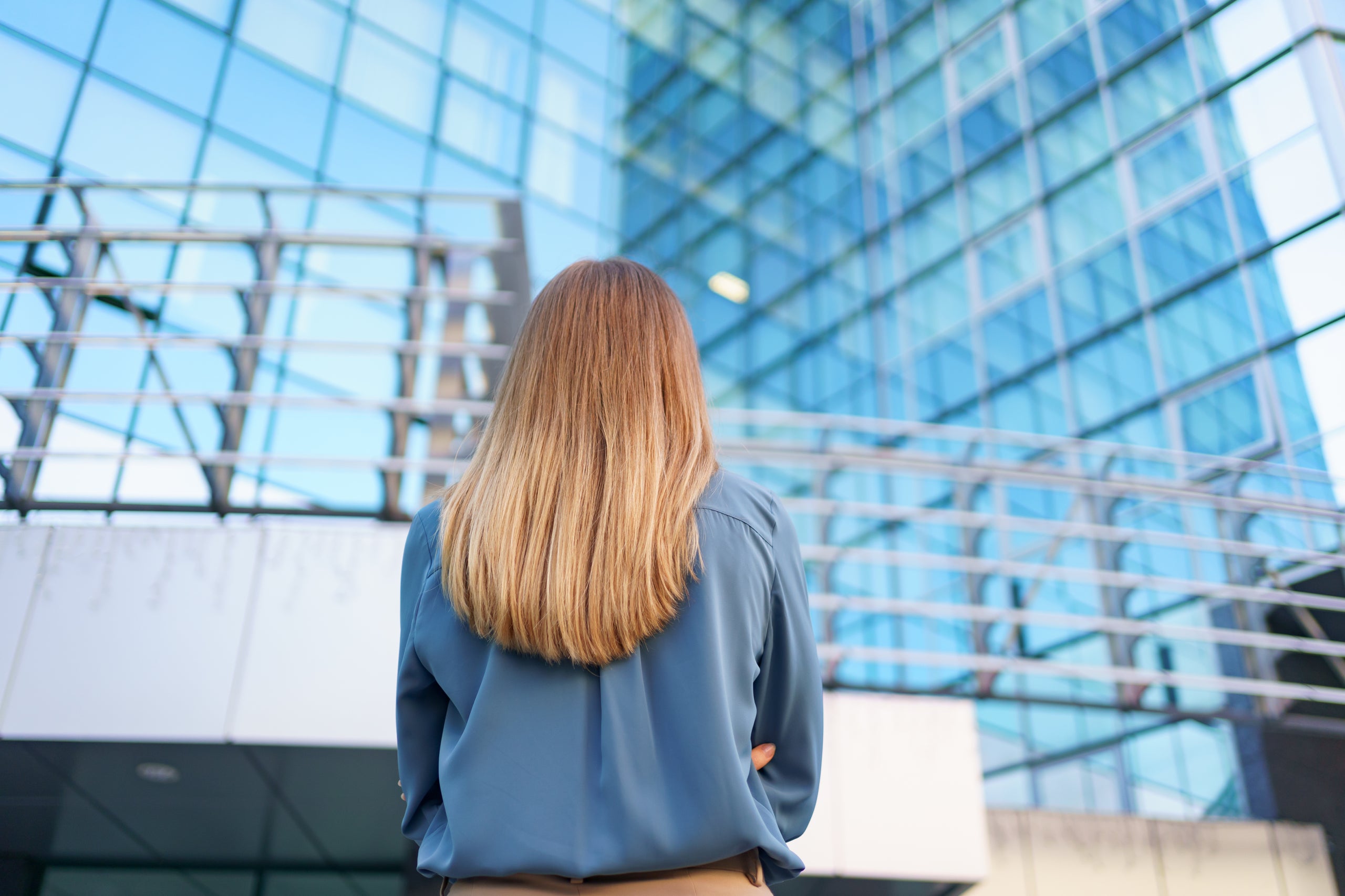 Back view of successful manager looking at business building of modern city.