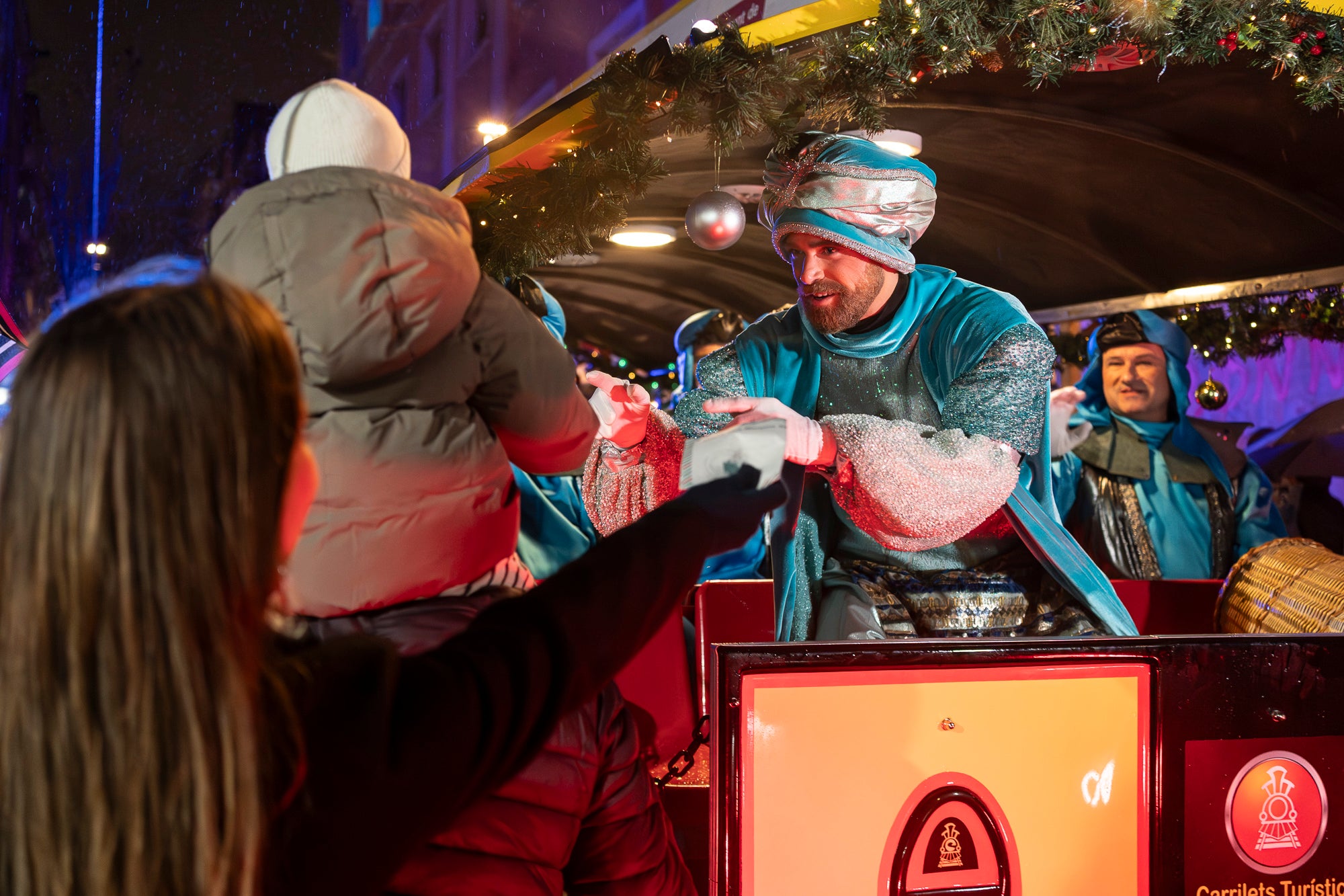 Malgrat unes condicions meteorològiques adverses, que han obligat a canviar l'itinerari de la corrua anant en trenet des de l'Estació del Nord i impedint que els Gegants de Terrassa poguessin acompanyar-lo baixant pel carrer de la Font Vella i es fes el Ball de l'Àliga al final, el patge Xiu-Xiu ha tingut la grata sorpresa a la seva arribada al Raval de Montserrat de trobar-se amb el seu capgròs com a regal pel seu 75 aniversari. Obra de l'artesà Jan Grau, el patge també compta a partir d'ara amb la seva figureta al pessebre oficial davant de l'Ajuntament. I des d'aquest dissabte i fins al 5 de gener, recorrerà els barris de la ciutat per recollir les cartes als Reis dels nens i nenes que s'hagin portat bé | Mireia Comas