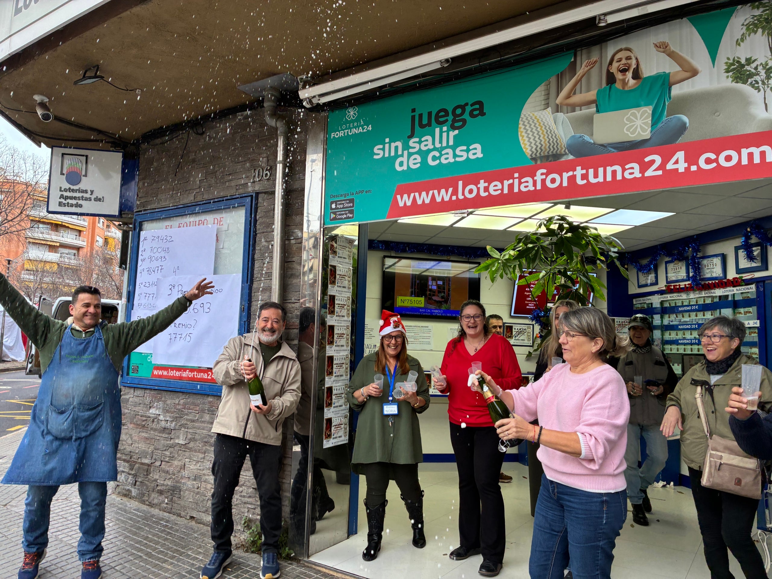 Els responsables de l'administració de loteria Fortuna 24 de Terrassa, amb el seu administrador José Manuel Valverde amb una ampolla, i algun veí més celebrant els premis de Nadal que han donat | Vicenç Batalla