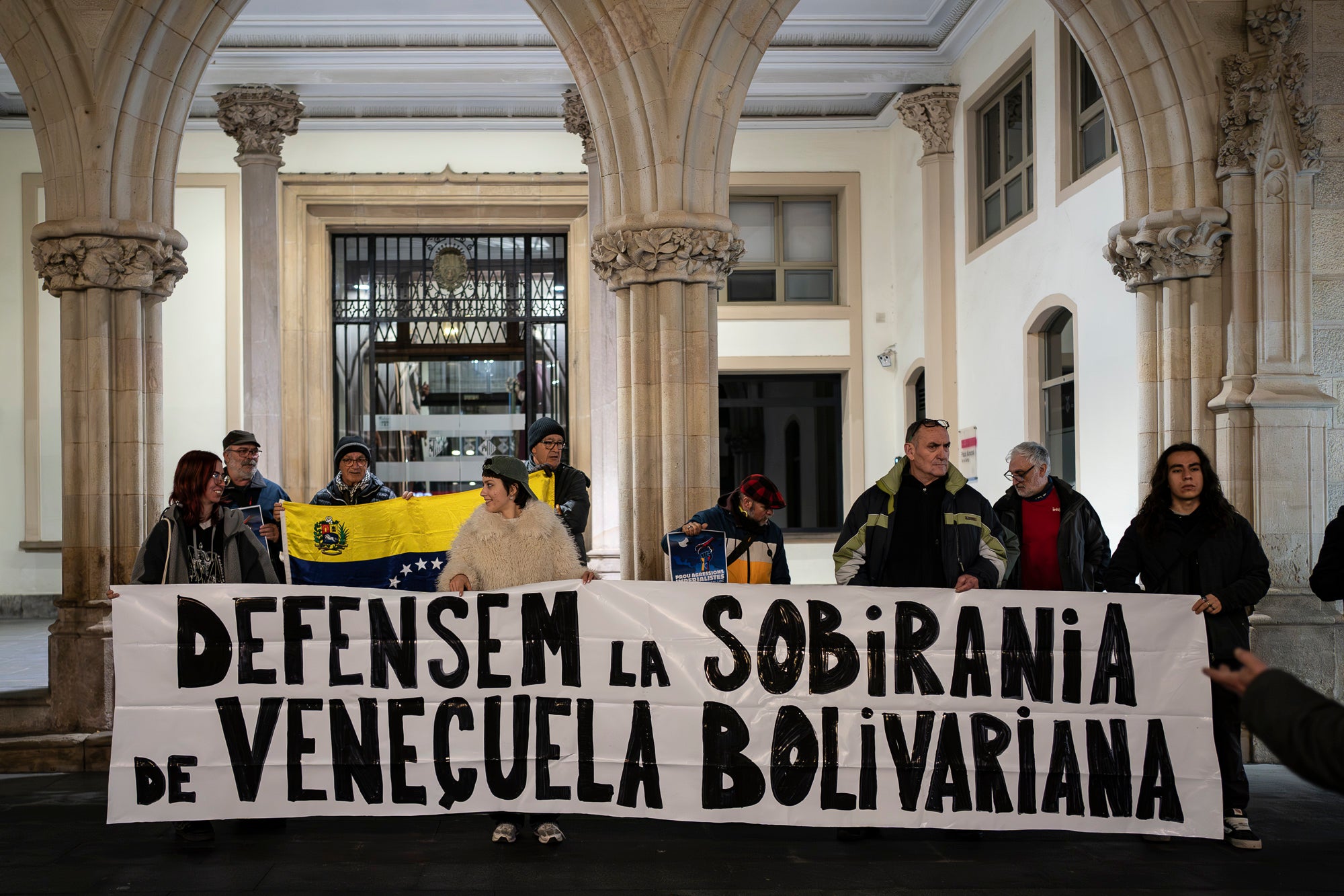 Acte de protesta aquest divendres, dia 16 de gener, davant de l’Ajuntament de Terrassa contra la intervenció militar dels EUA a la República Bolivariana de Veneçuela, del passat 3 de gener. La concentració ha estat convocada pel Comitè Bolivarià de Terrassa ha demanat a la Unió Europea mediar per una resolució diplomàtica i pacífica dels conflictes, “trencant amb el vassallatge i la dependència dels Estats Units”, així com ha exigit l’alliberament “immediat” del president Nicolás Maduro i de la diputada Cilia Flores. 