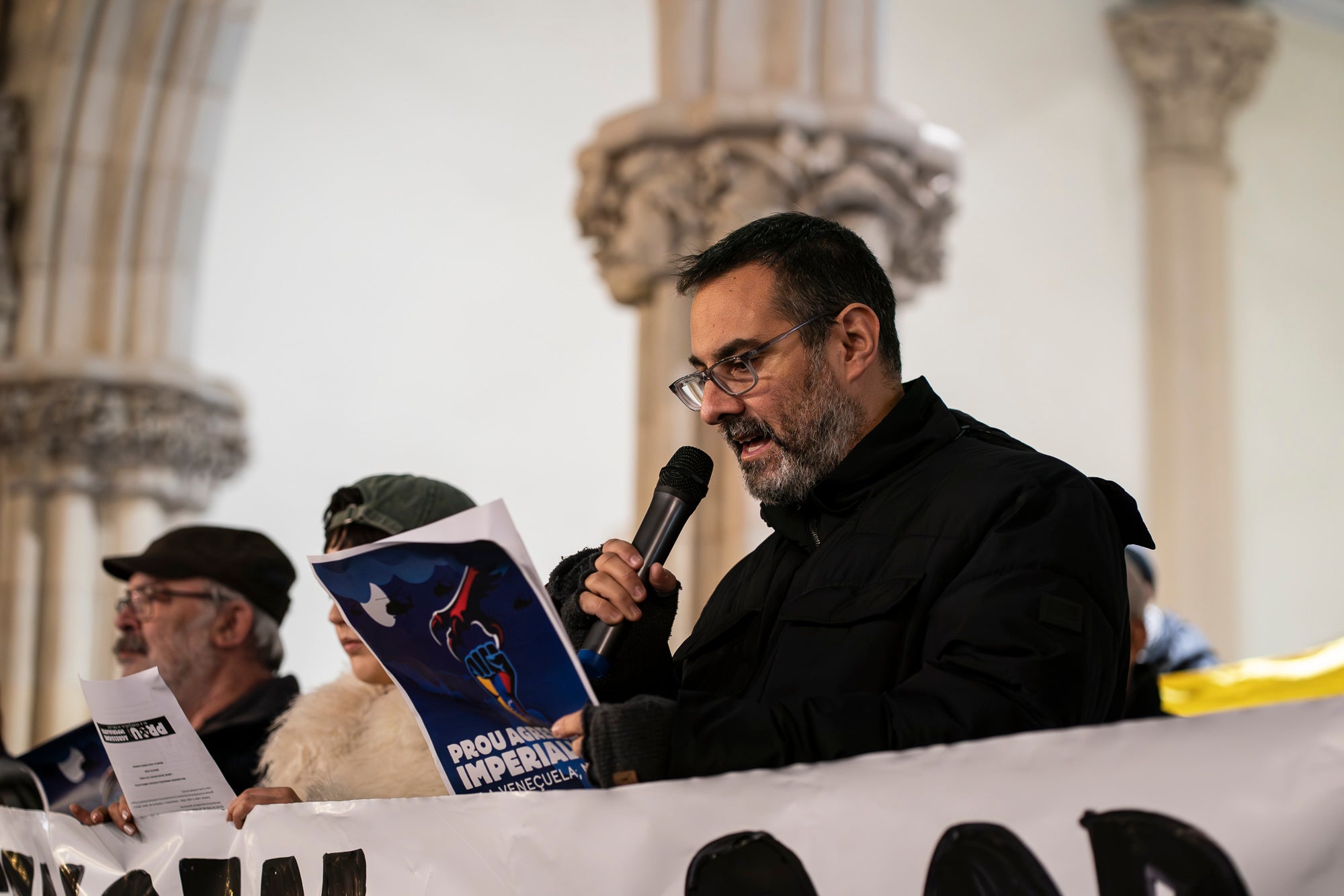 Acte de protesta aquest divendres, dia 16 de gener, davant de l’Ajuntament de Terrassa contra la intervenció militar dels EUA a la República Bolivariana de Veneçuela, del passat 3 de gener. La concentració ha estat convocada pel Comitè Bolivarià de Terrassa ha demanat a la Unió Europea mediar per una resolució diplomàtica i pacífica dels conflictes, “trencant amb el vassallatge i la dependència dels Estats Units”, així com ha exigit l’alliberament “immediat” del president Nicolás Maduro i de la diputada Cilia Flores. 