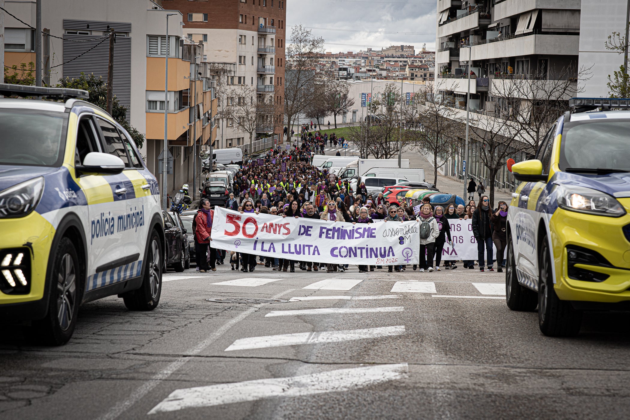 Per primera vegada, aquest 2026 la manifestació del 8M no ha acabat al Raval de Montserrat davant de l'Ajuntament de Terrassa sinó als simbòlics Jardins d'Eva Abad, a Torre-sana, en homenatge a la metgessa assassinada el 2019. Des de la plaça de la Dona, la desfilada feminista d'aquest any ha baixat per l'avinguda de Barcelona per girar cap a l'est i anar a la plaça de Ca n'Anglada, coneguda com 'la Roja' durant el franquisme, on s'ha llegit el manifest 50 anys de feminisme i la lluita continua! i hi ha hagut altres parlaments. Entre la desena d'entitats, encapçalades pel Casal de la Dona, que enguany compleix 40 anys, n'hi havia més d'una de barris però també les anticapitalistes Rudes Rebels. La desfilada ha acabat entonant les cançons Les criades i Cant de lluita | Javi Sánchez