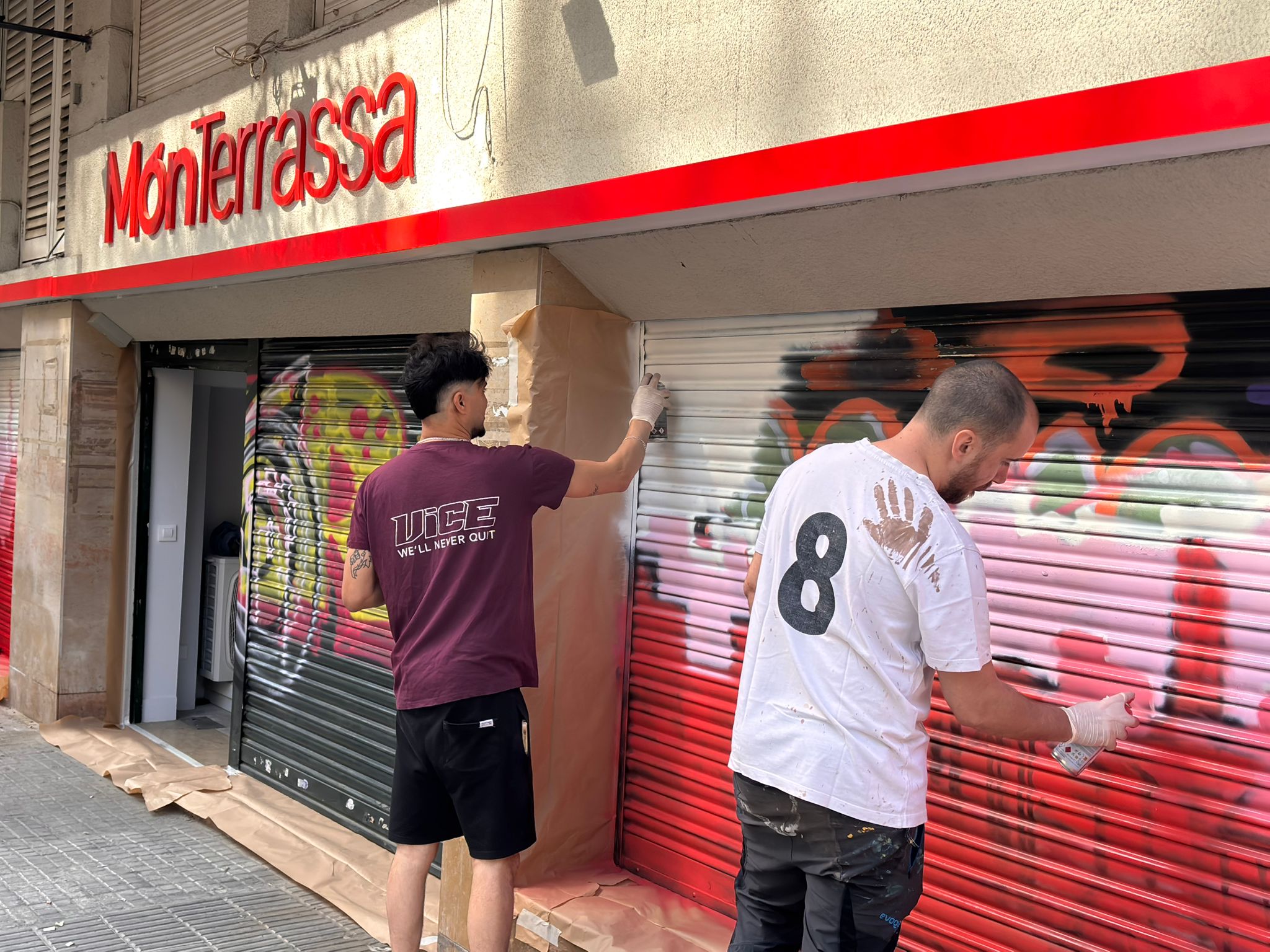 Mohi Lee i Jordi Rosset (TwooCanStudio) realitzant en grafrit l'skyline a les persianes de la nova seu de Mónterrassa | Joan Gil