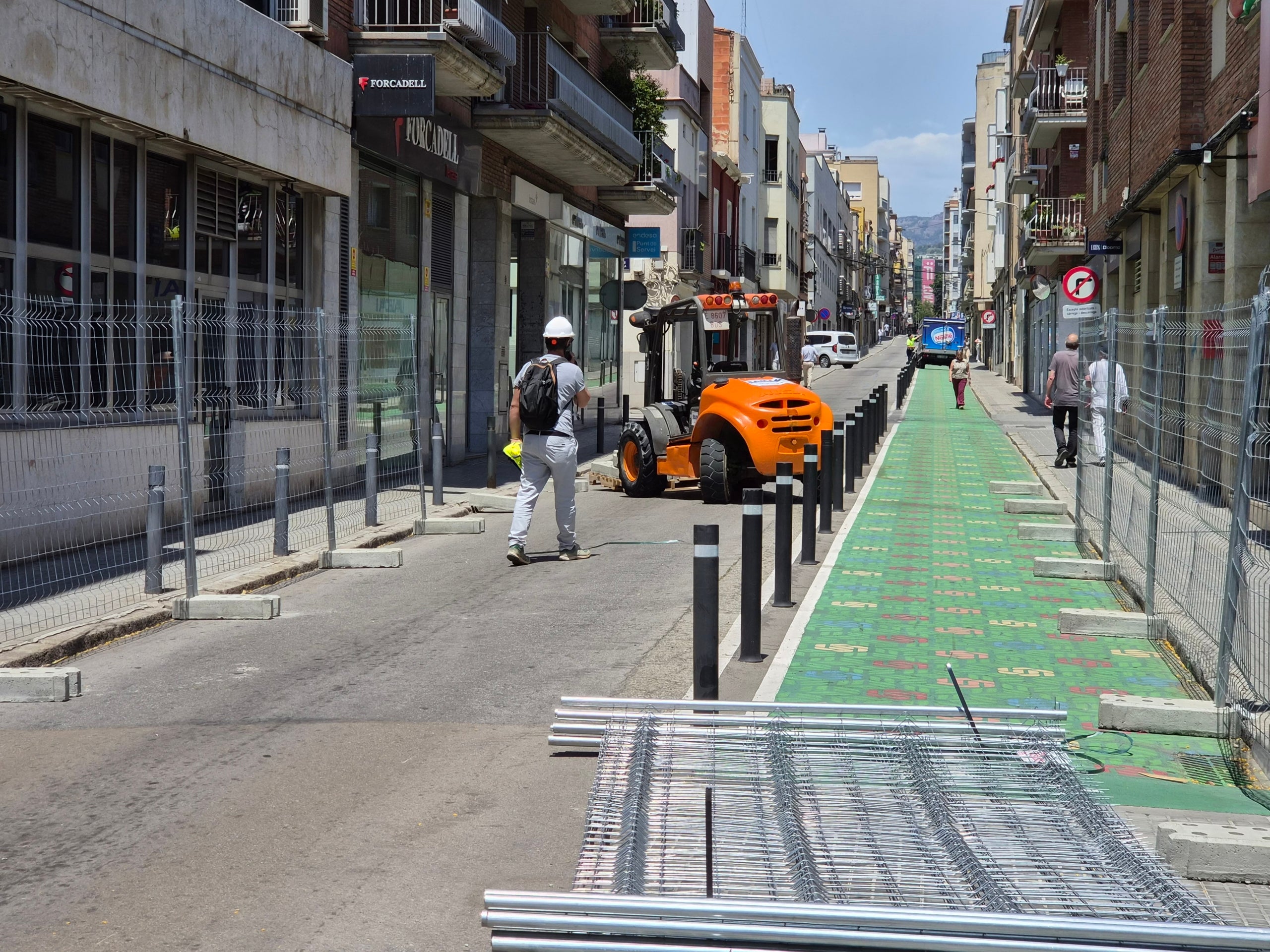 Aquest dilluns dia 15 de juny han començat les obres de pacificació del carrer d’Arquimedes de Terrassa. Des de bon matí, operaris han estat col·locant les tanques i cartells amb les afectacions de trànsit advertint els conductors des de la carretera de Martorell. I és que ha quedat totalment tallada la circulació entre plaça del Progrés i Grànius. D’aquesta manera, malgrat que la voluntat de l’Ajuntament és que els vehicles ja no entrin per Arquimedes per creuar la ciutat cap al nord, han estat molts que s’han esperat fins a trobar la reixa metàl·lica que impedia el pas per buscar una alternativa. Cal dir que no ha estat fins passades les dotze del migdia quan no s’ha tancat definitivament. Fins aleshores, els vehicles podien passar, tot i que diversos agents de la Policia Municipal de Terrassa, repartits al llarg d’Arquimedes, informaven els conductors de l’actuació. Recordem que la previsió és finalitzar les obres el febrer de 2027, i la voluntat del Consistori és aconseguir en aquest temps un canvi real d’hàbits i donar impuls a l’ús de les rondes de la ciutat.