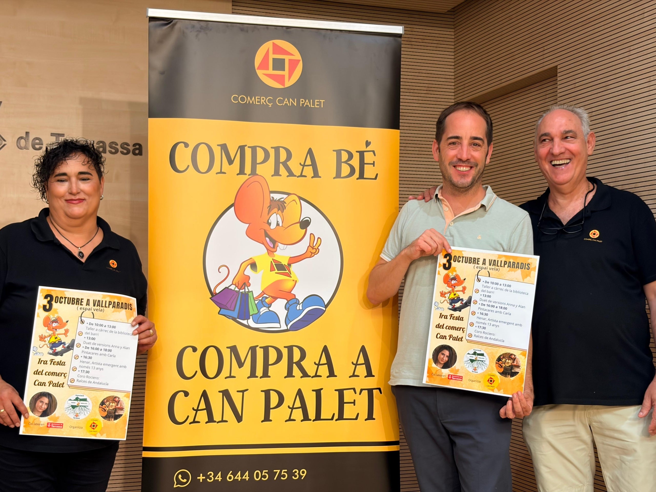 El regidor de Comerç de Terrassa, Xavier Cardona, amb la secretària i el president de Comerç Can Palet, Olívia Ferre i Francisco Viciana, al seu costat amb el cartell de la primera Festa del Comerç del barri al parc de Vallparadís | Aj. Terrassa 