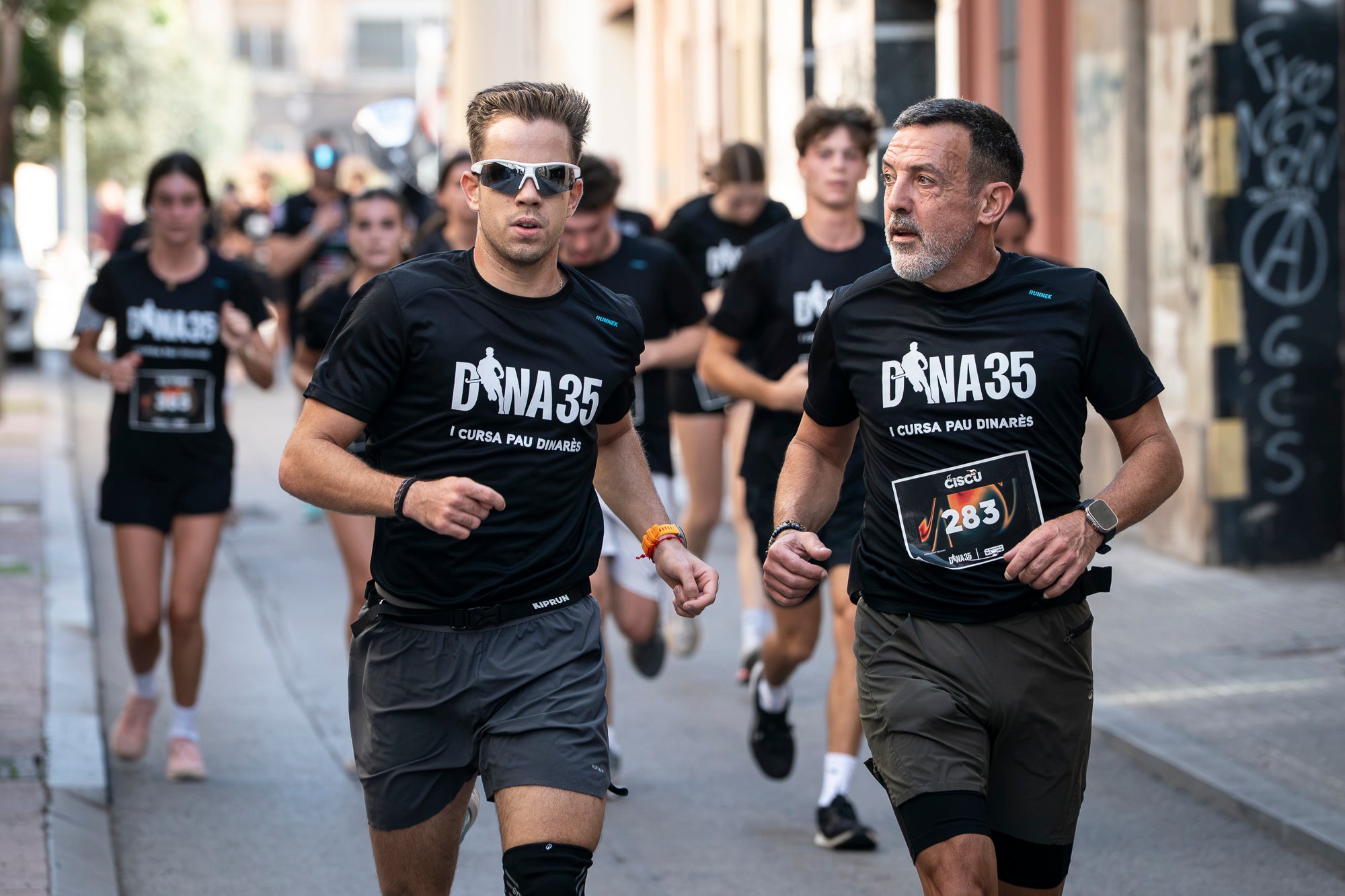 Segurament els guanyadors eren el de menys, però aquests vencedors i els seus temps li donen més relleu a la I Cursa Solidària Pau Dinarès disputada aquest diumenge a Terrassa per recaptar fons en la investigació de l'osteosarcoma. En categoria masculina, ha estat la jove promesa terrassenca Àlex Pintado qui ha travessat primer la meta del recorregut de 10 quilòmetres urbans amb 30 minuts i 52 segons, mentre que en categoria femenina ha estat primera la veterana egarenca Sandra Asín, amb 37 minuts i 32 segons. L'arribada i sortida es feia al parc dels Catalans i el moment més simbòlic era el pas per davant del carrer de Suris, on viu la família de Pau Dinarès, jove atleta d'hoquei sobre herba de l'Egara que va morir el novembre passat als 22 anys d'aquest càncer i en memòria de qual l'associació Dina35 ha creat aquesta prova | Mireia Comas