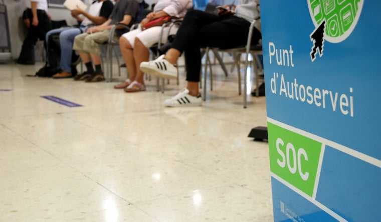 Sala interior d'una oficina del Servei d'Ocupació de Catalunya (SOC) on es veuen els peus d'uns aturats asseguts a la sala d'espera  | ACN